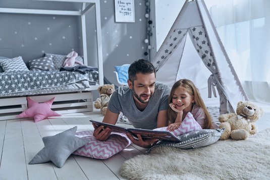 Vater und Tochter lesen ein Buch.