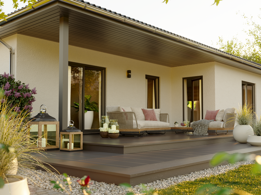 Frontale Nahaufnahme der Terrasse des Winkelbungalow 108 mit bodentiefen Fenstern, modernen Sitzmöbeln und Blumenschmuck bei Tageslicht.